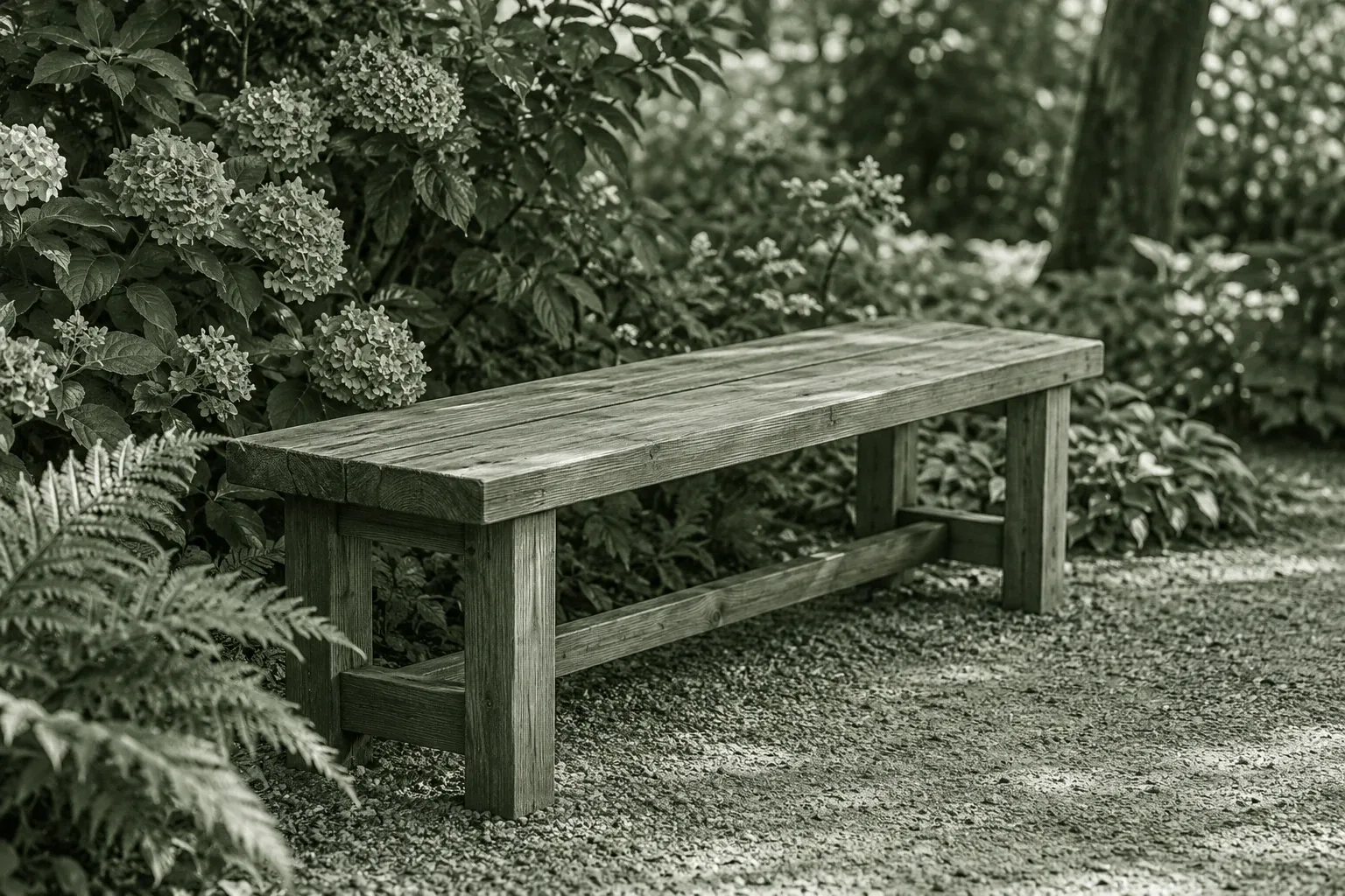 Schlichte Holzbank im Garten auf Kiesweg, umgeben von Farnen und blühenden Hortensien